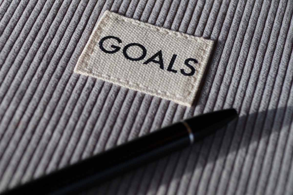 A sewn clothing tag with goals written on it next to a black pen